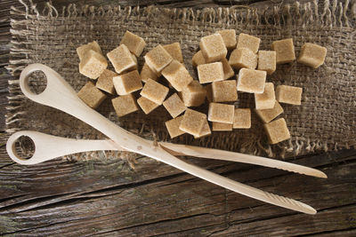 High angle view of sweet food with scissor on sack over wooden table