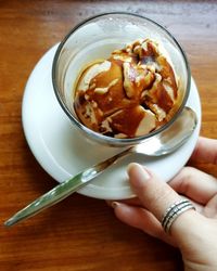 Cropped hand holding ice cream at table