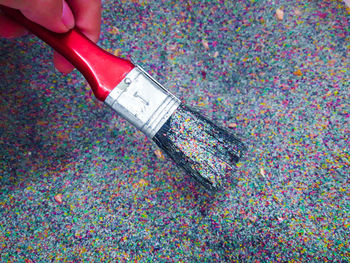 Cropped hand holding paintbrush with glitters