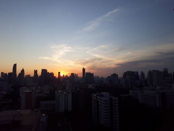 Modern buildings in city against sky during sunset