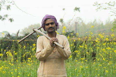 Portrait of indian farmer in the field carrying hoe and sickle