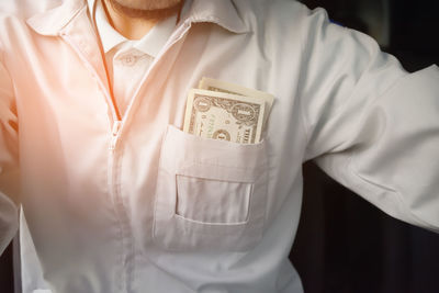 Midsection of man with paper currency in pocket