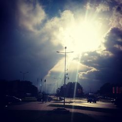 Cars on road against cloudy sky