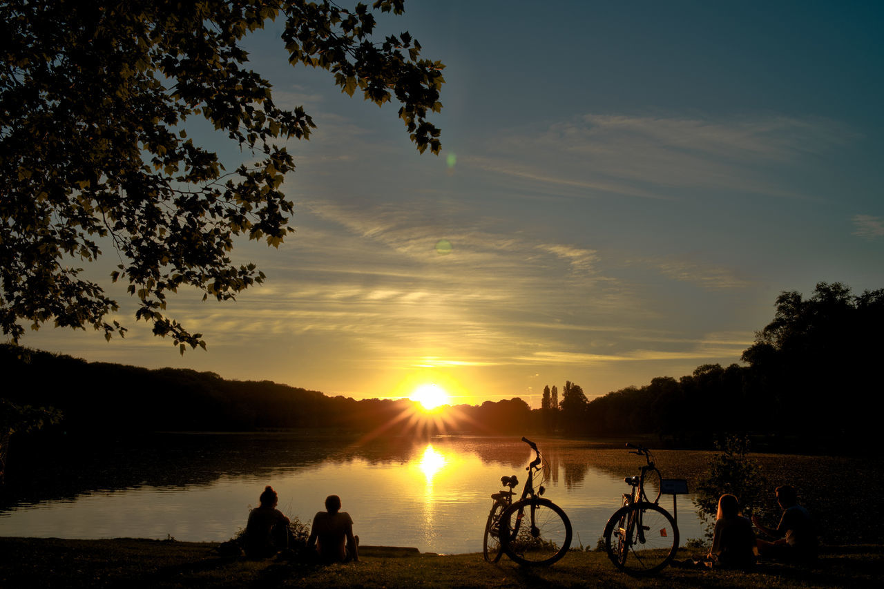 sunset, sky, silhouette, water, beauty in nature, tree, orange color, real people, group of people, scenics - nature, men, plant, cloud - sky, nature, leisure activity, bicycle, tranquility, lifestyles, sun, outdoors