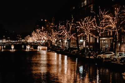 Illuminated buildings by river at night