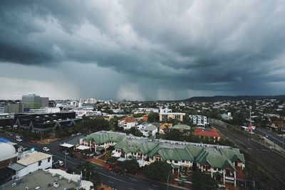High angle view of buildings in city against storm clouds