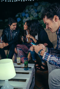 Man using phone while sitting with friends at patio