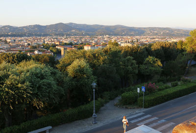 High angle view of woman crossing road by trees in city