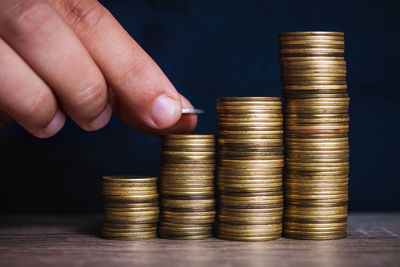 Close-up of hand stacking coins on table