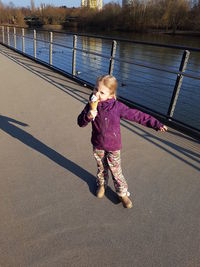 Portrait of cute girl eating ice cream while standing on footbridge