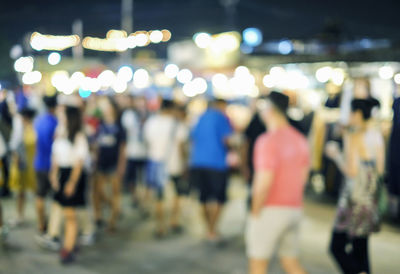 Defocused image of people walking in illuminated city at night