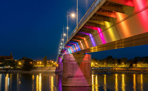 Illuminated bridge over river against sky at night