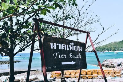 Information sign on beach against sky