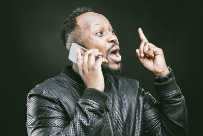 Man talking on mobile phone against wall