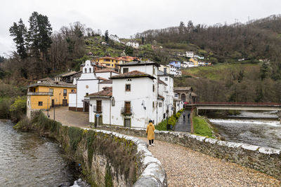 Houses by river amidst buildings against sky