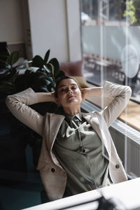 Businesswoman with hands behind head resting in office