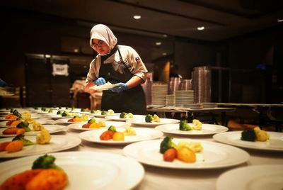 Woman arranging food on table in restaurant