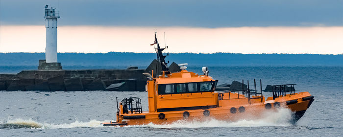 Nautical vessel on sea by buildings against sky