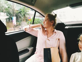 Smiling woman with daughter sitting in car