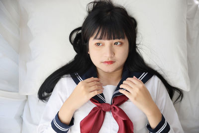 Portrait of young woman looking away against wall