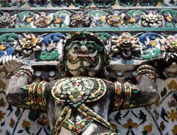 A decorative and colorful statue on the facade of wat arun, the temple of dawn, in bangkok, thailand