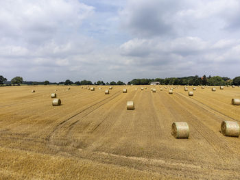 Hay bales on field against sky