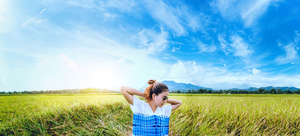 Rear view of woman standing on field against sky