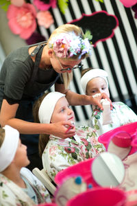 Girls looking at beautician applying cream on friend face at spa