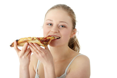 Portrait of a smiling young woman eating food against white background