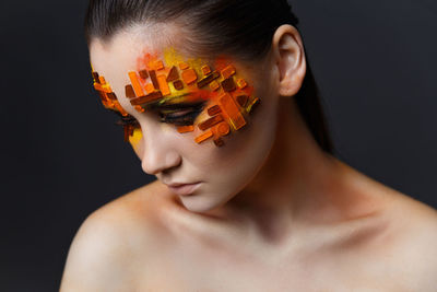 Close-up of woman with decorated face make-up against black back background