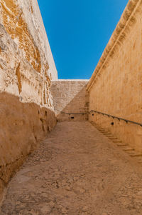 Low angle view of brick wall against clear blue sky