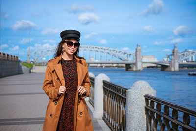 Beautiful young woman in a raincoat on the embankment