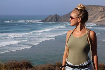 Young woman looking away while standing on beach