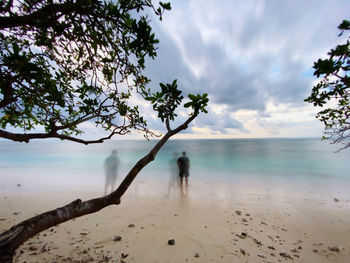 Motion blur of  man standing alone at the turquoise beach thinking with scenics view of blue sky
