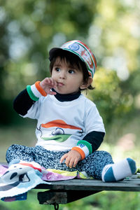 Portrait of cute baby boy sitting on field