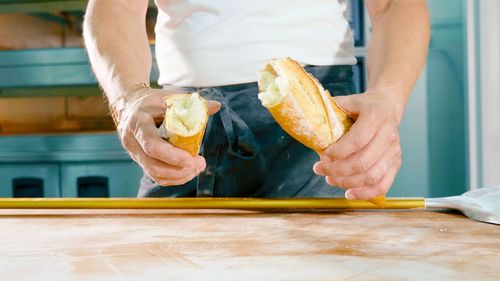 Midsection of man holding bread while standing by table