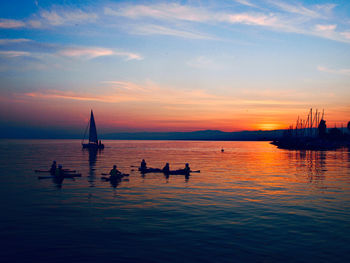 Silhouette sailboats in sea against sky during sunset