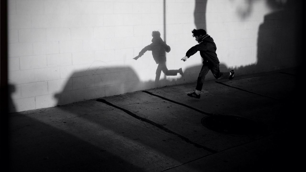 shadow, lifestyles, men, full length, walking, leisure activity, sunlight, street, person, tiled floor, togetherness, day, high angle view, sidewalk, flooring, footpath, paving stone, childhood