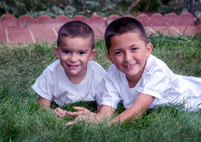 Portrait of two smiling brothers posing in the grass