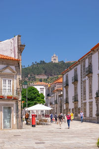 People on buildings in city against clear sky