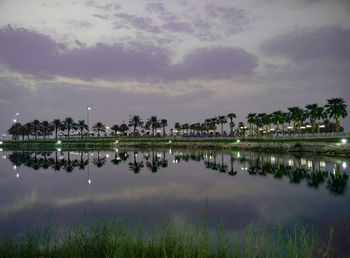 Reflection of trees in lake against cloudy sky