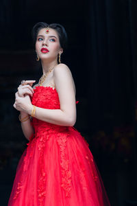 Portrait of a beautiful young woman standing against black background