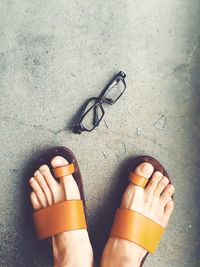 Low section of person standing by broken eyeglasses on floor