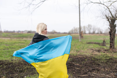 Woman holding flag in field