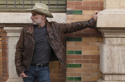 Portrait of adult man in cowboy hat against building