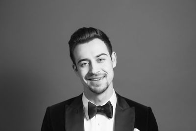 Close-up portrait of young man in suit standing against black background