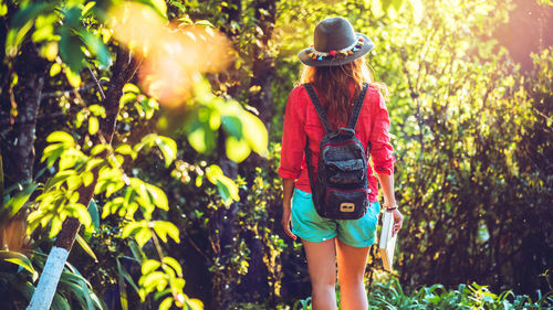 Rear view of woman with umbrella walking on plants