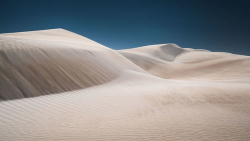 Sand dunes in desert against clear sky