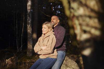 Couple resting in forest at sunny day