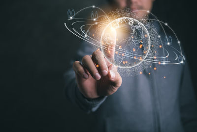 Midsection of person holding sparkler against black background